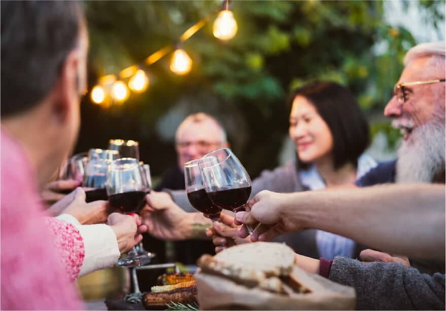 A group of friends make a toast with glasses of red wine in an early dinner.